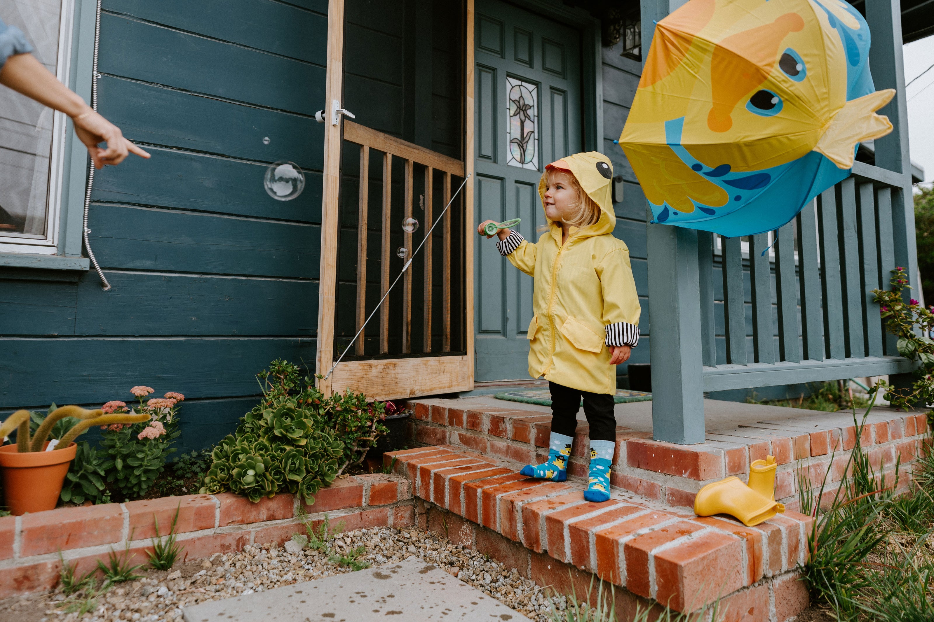 "photo of child standing on brick front porch wearing ahoy rubber duck kid's socks"
