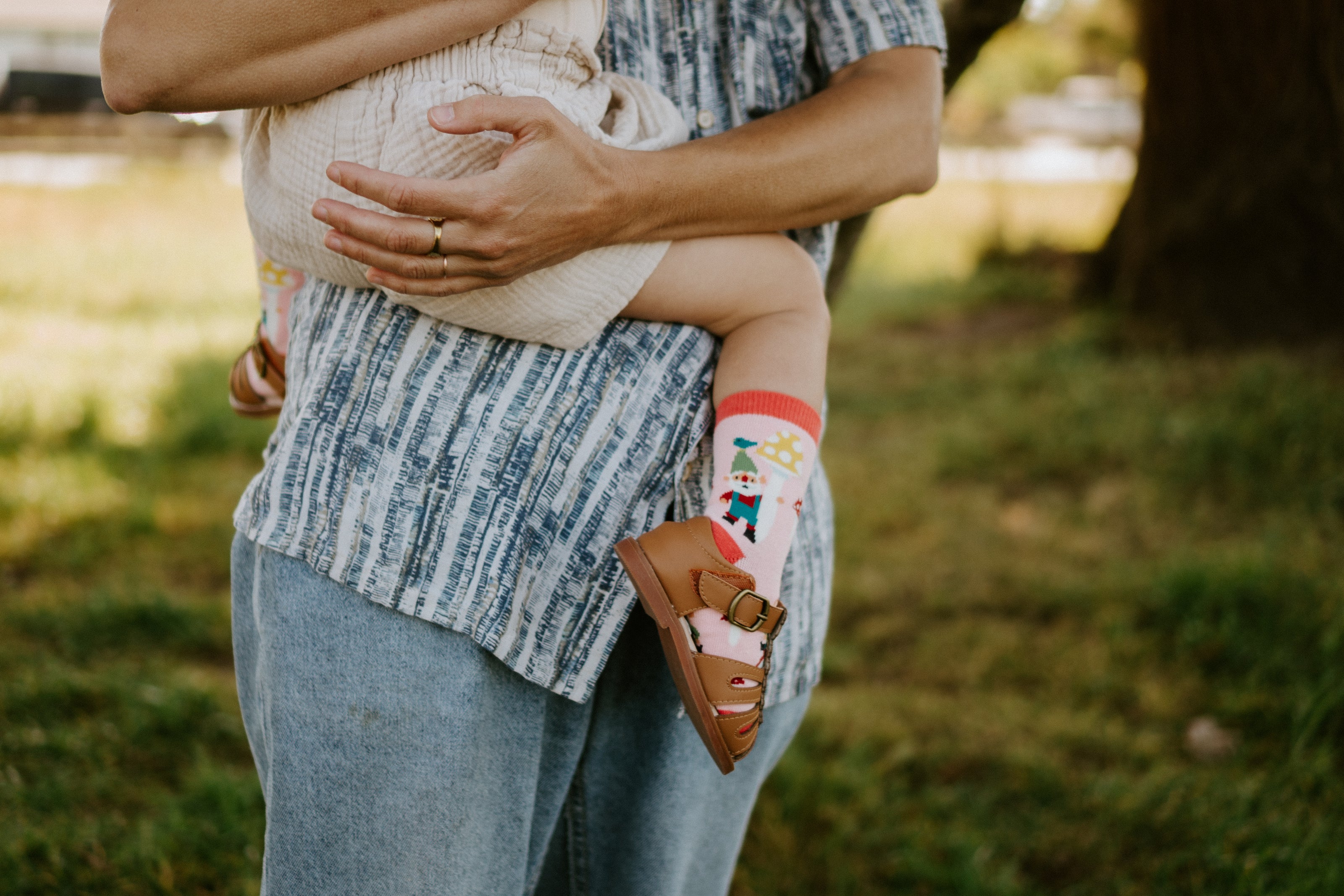 "child being held by adult, child wearing gnome garden kid's socks"