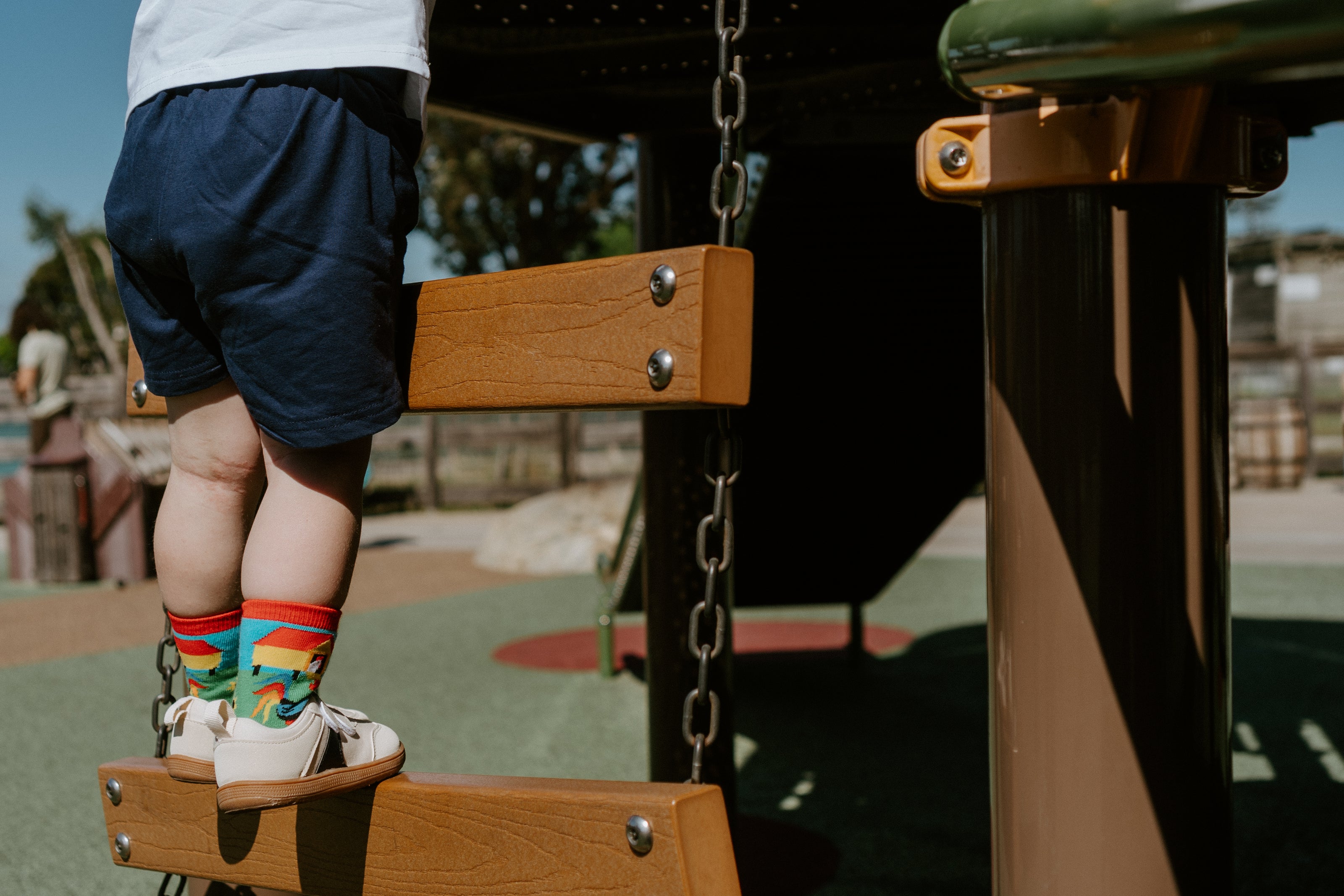 "child at park on playground ladder wearing mo chickens kid's socks"