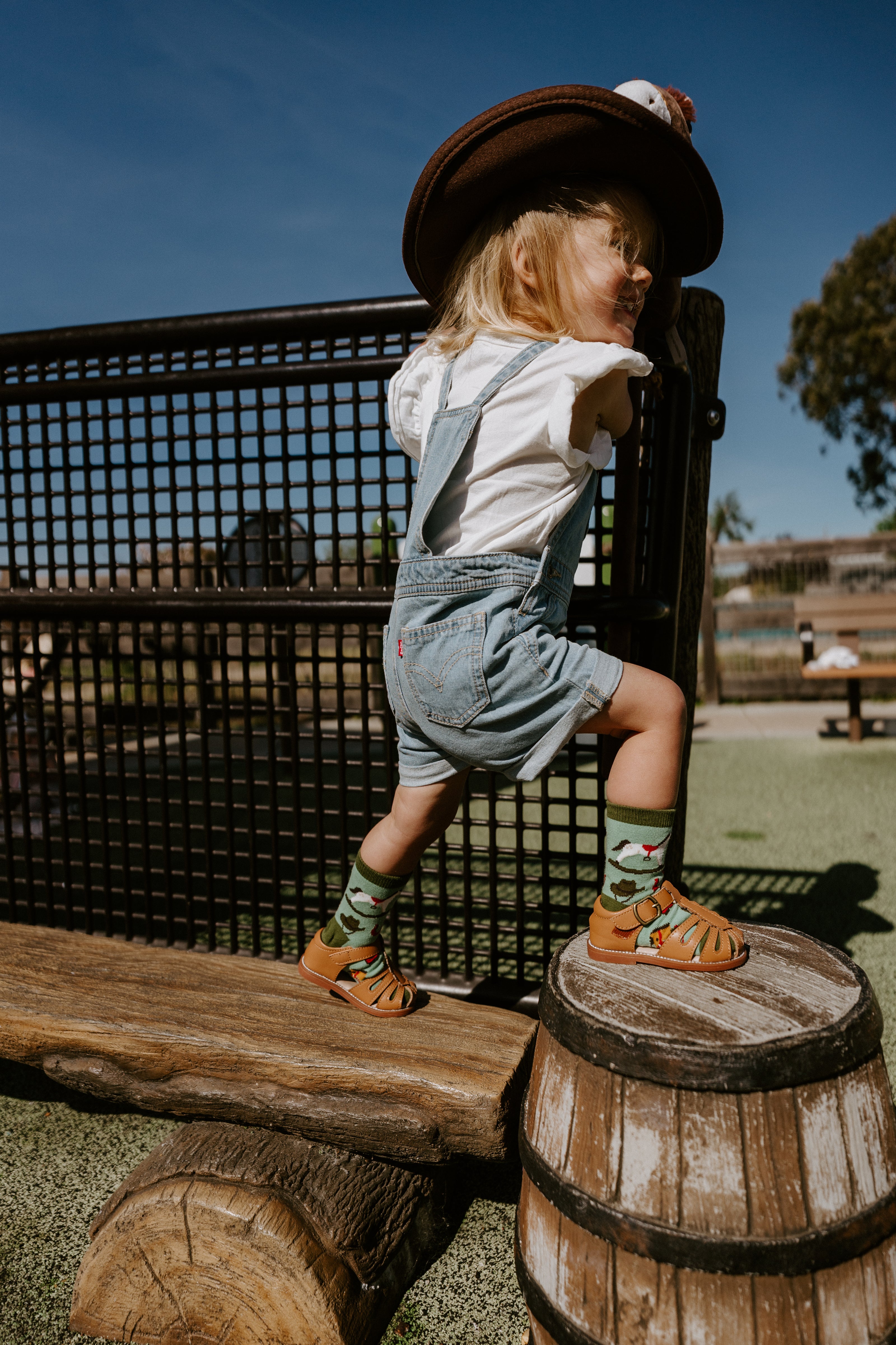 "child at playground wearing cowboy hat and pony up kids socks"