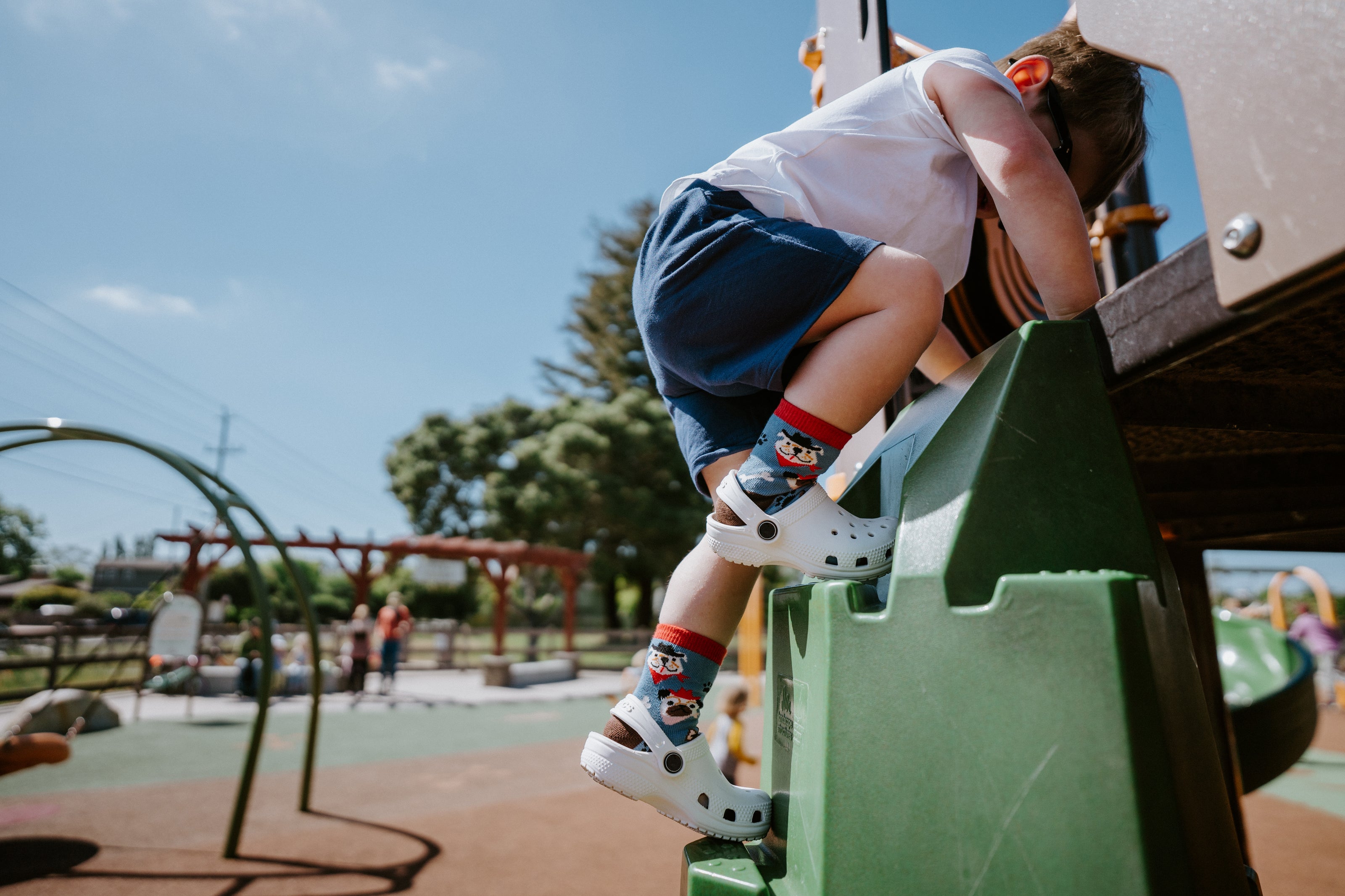 "child playing at playground while wearing saddle up pups kids socks"