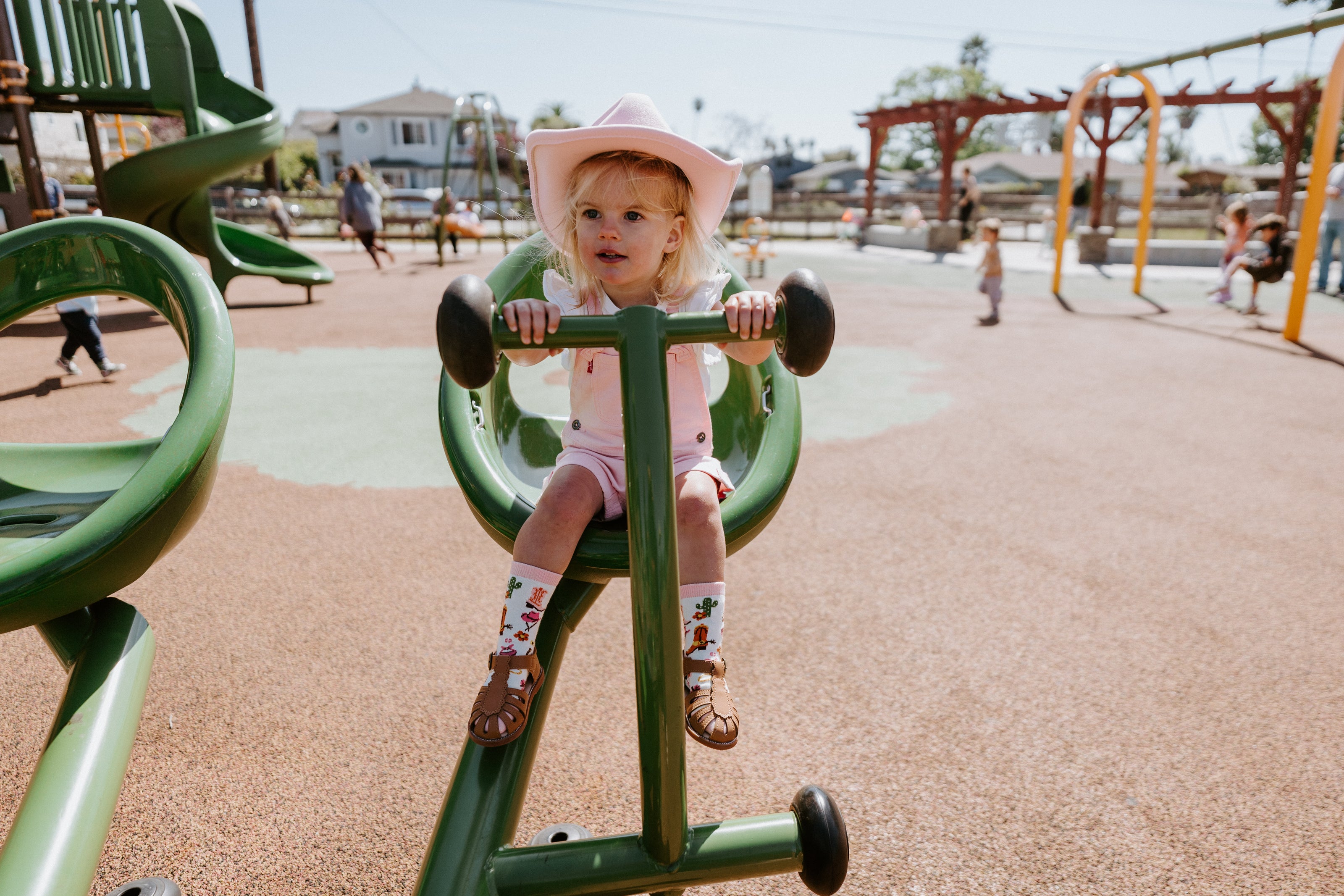 "child at playground wearing pink cowgirl hat and yee haw cowgirl kids socks"