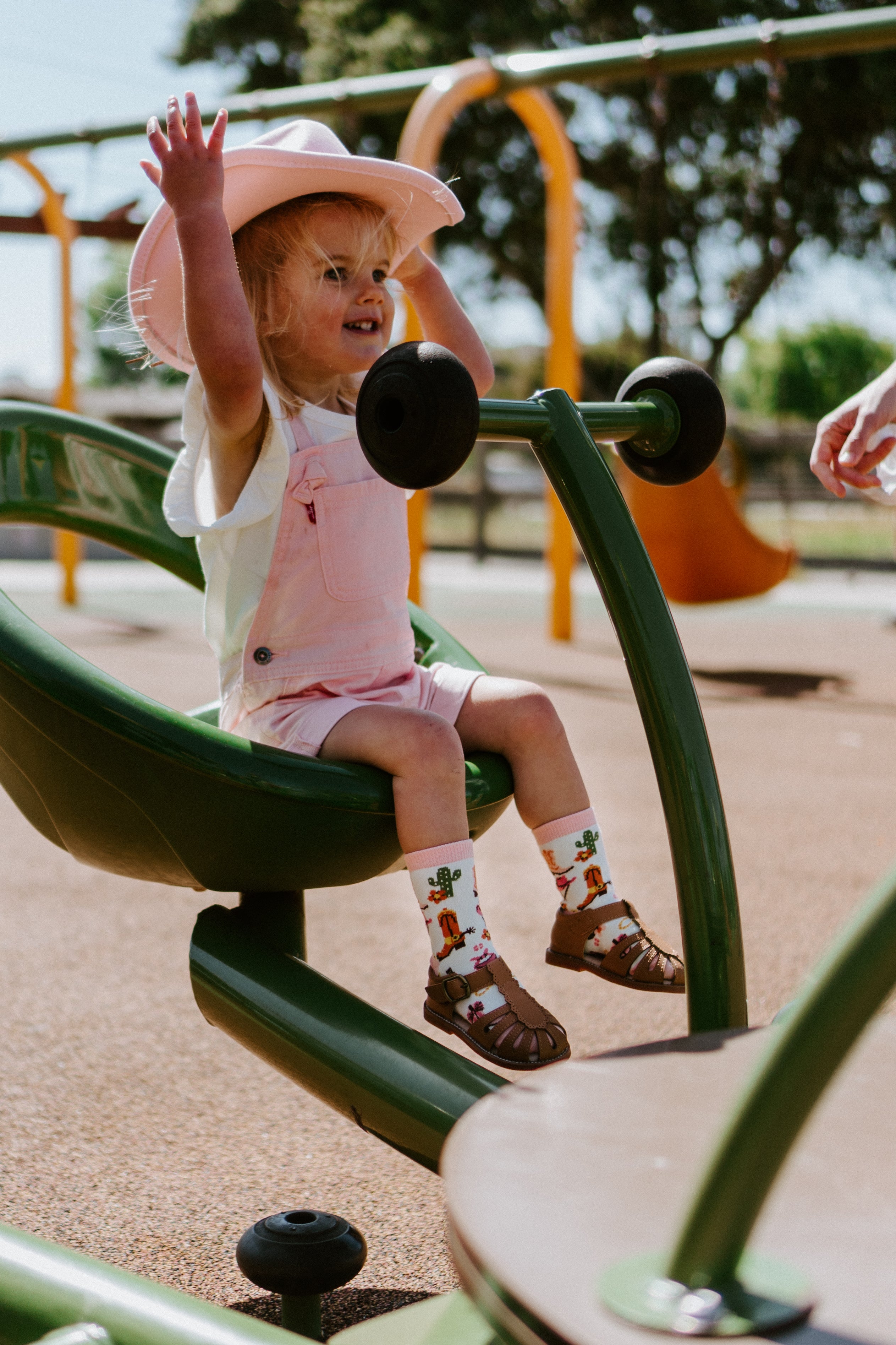 "child at playground wearing pink cowgirl hat and yee haw cowgirl kids socks"