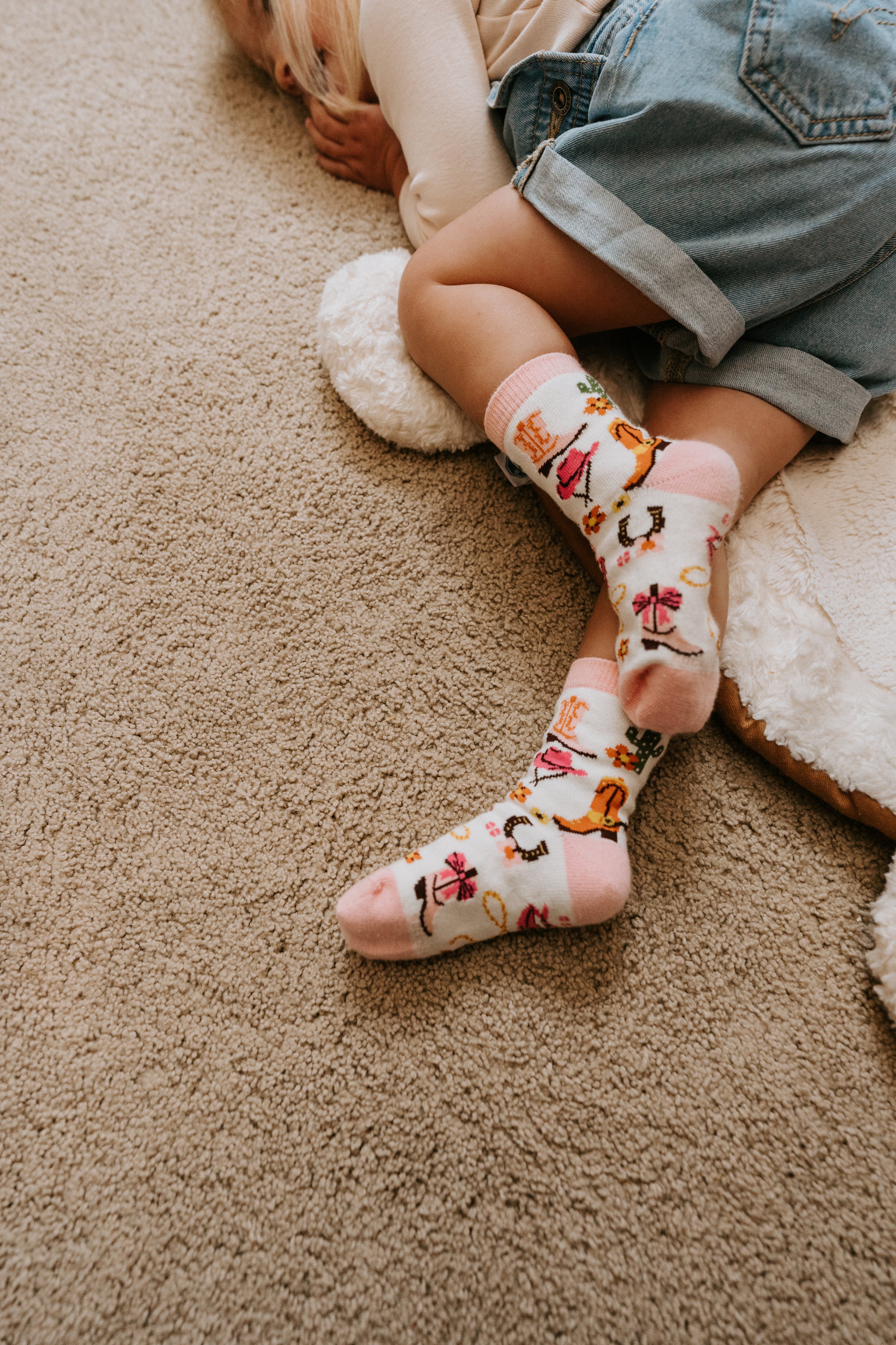 "child laying on floor wearing yee haw cowgirl kids socks"